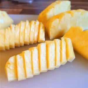The pineapple wedges are cut into slices.