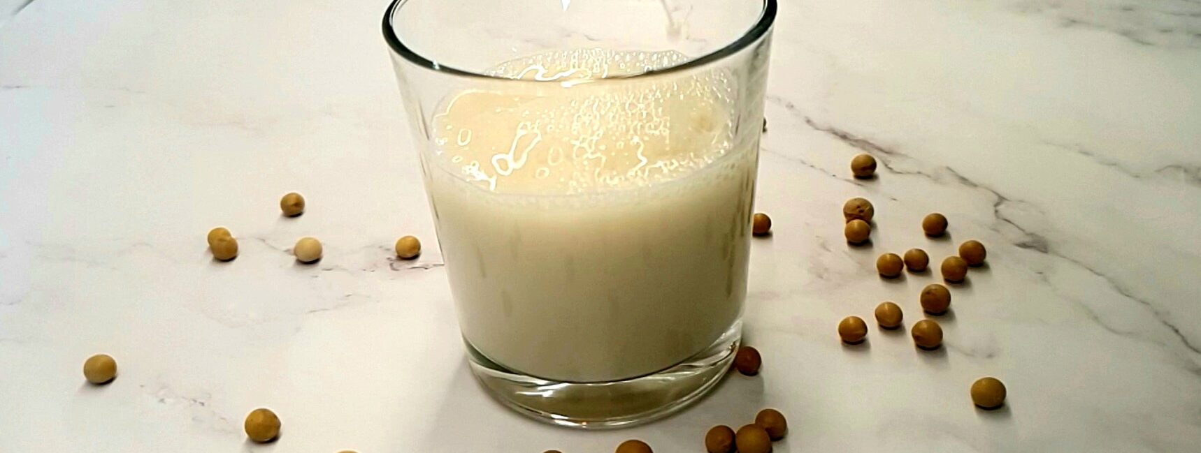 Soy milk being poured into a glass.