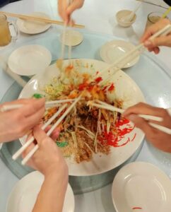 Tossing Yee Sang high to have good fortune.