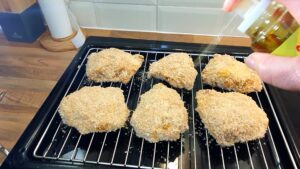 Spraying oil on the chicken before baking.